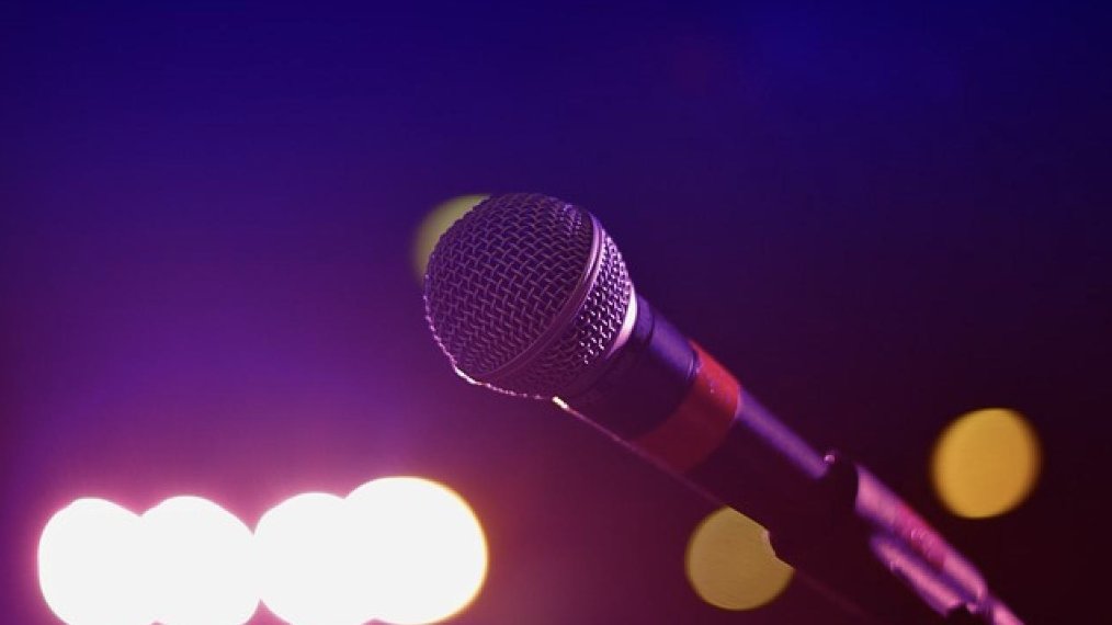 Microfoon op een standaard in paars en roze podiumlicht