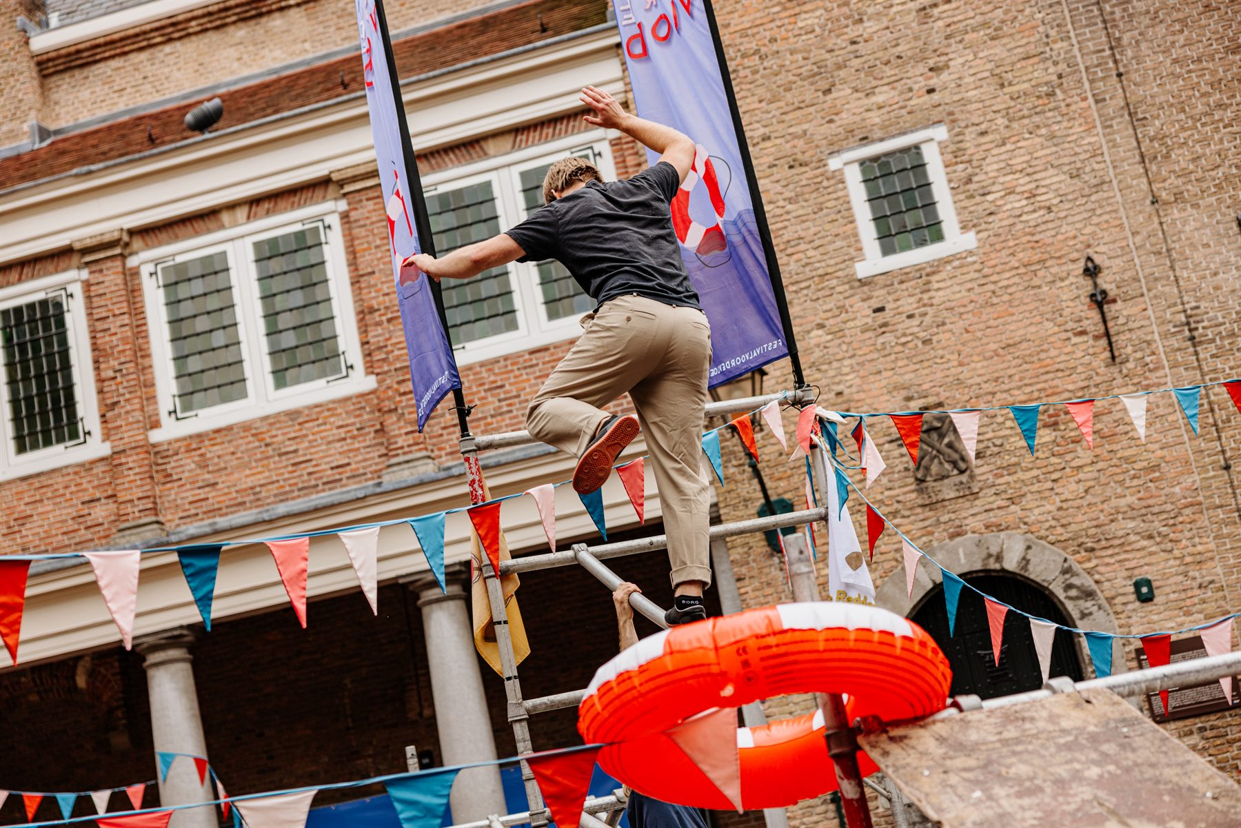Bezoeker klimt over een steiger tussen de festivalvlaggen