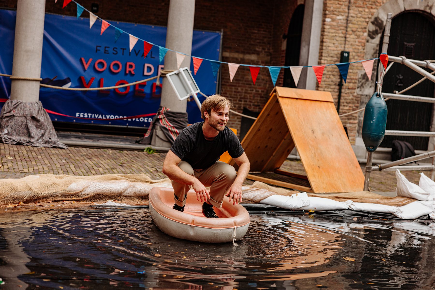 Bezoeker vaart hurkend in een drijvende teil door het water op Het Hof